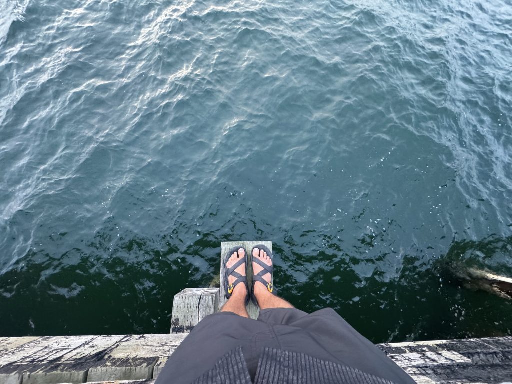 I_Am_Getting_Married_v1.zip 4 Tukayote's feet in flip flops dangling over the water from Little Squalicum Pier