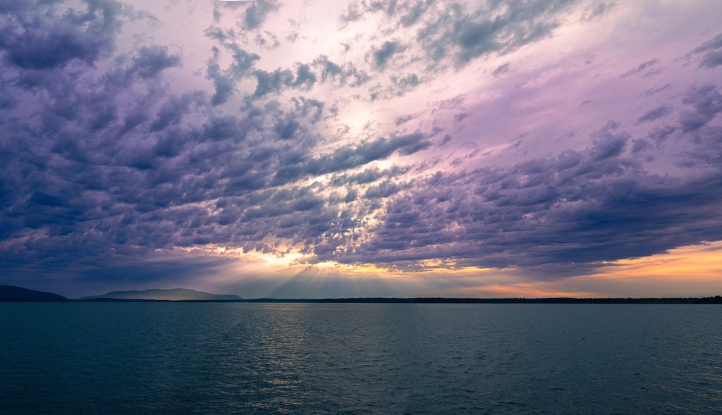 Severed_v1.zip 19 Sun rays breaking through dramatic purple clouds over the water