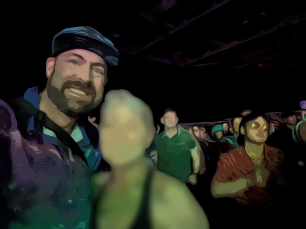 Stylized, painterly selfie of Tukayote smiling in a dark room at a rave, with a friend's blurred face beside him and a crowd dancing behind them