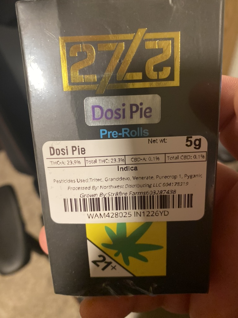 Hand holding a black and gold 5 gram box of Dosi Pie indica pre-rolled cannabis joints, with a lab label showing about 23 percent THC and a 21 plus symbol