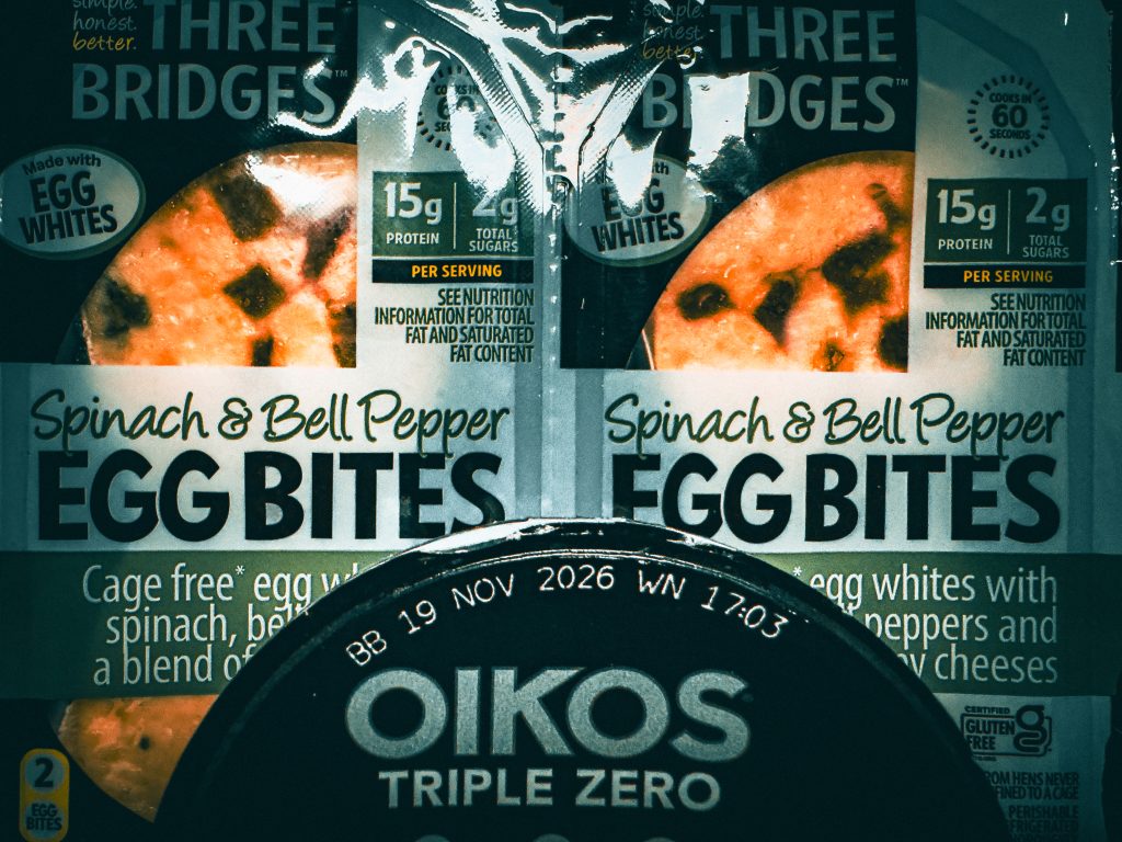 Close-up of Three Bridges spinach and bell pepper egg bites and the lid of an Oikos Triple Zero yogurt cup
